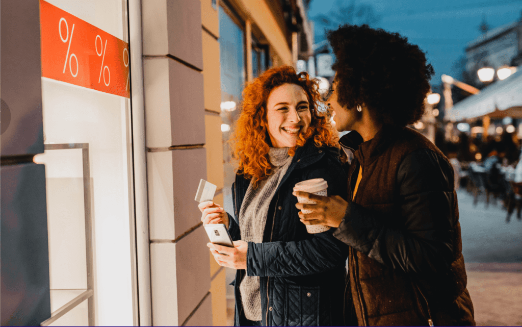 Two women smiling and using a through the wall ATM