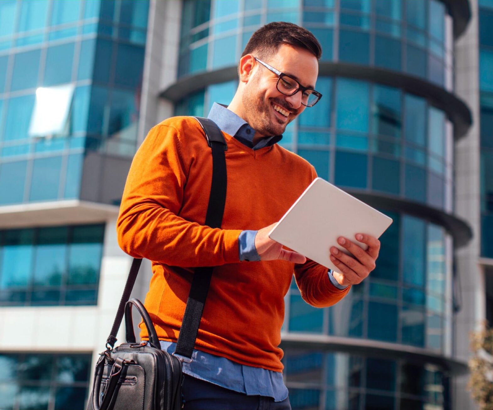 Man smiling in the city and using an Ipad