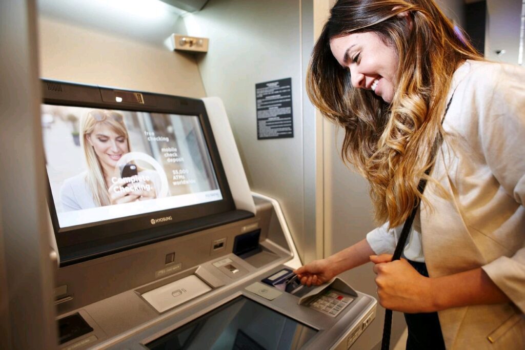 Woman happily inserting her card into an ATM